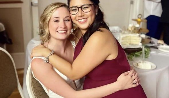 one woman sits on another woman's lap at a wedding 